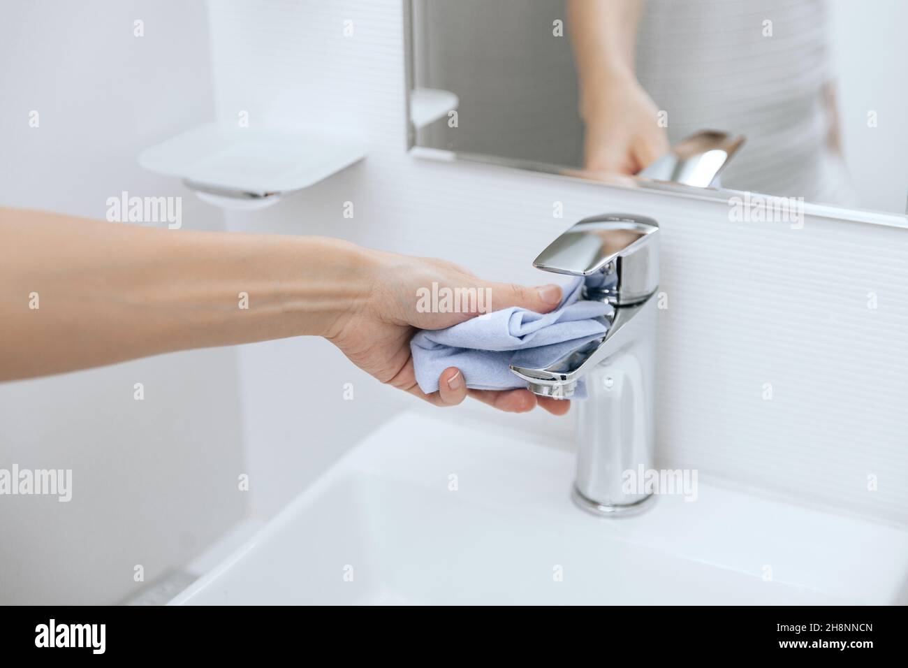 Cleaning the sink faucet with a microfiber cloth. Cleaning the bathroom