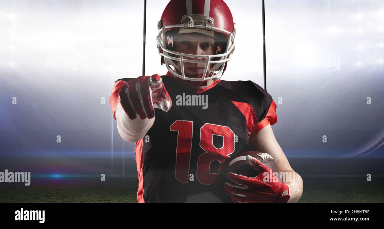 Portrait of confident male player holding ball challenging you for american football match Stock Photo