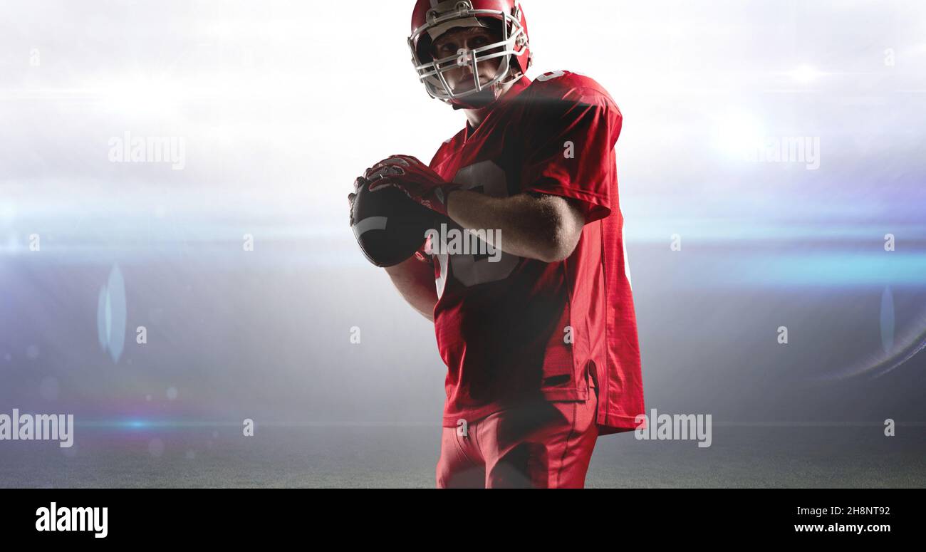 Male american football player about to throw ball at illuminated stadium Stock Photo