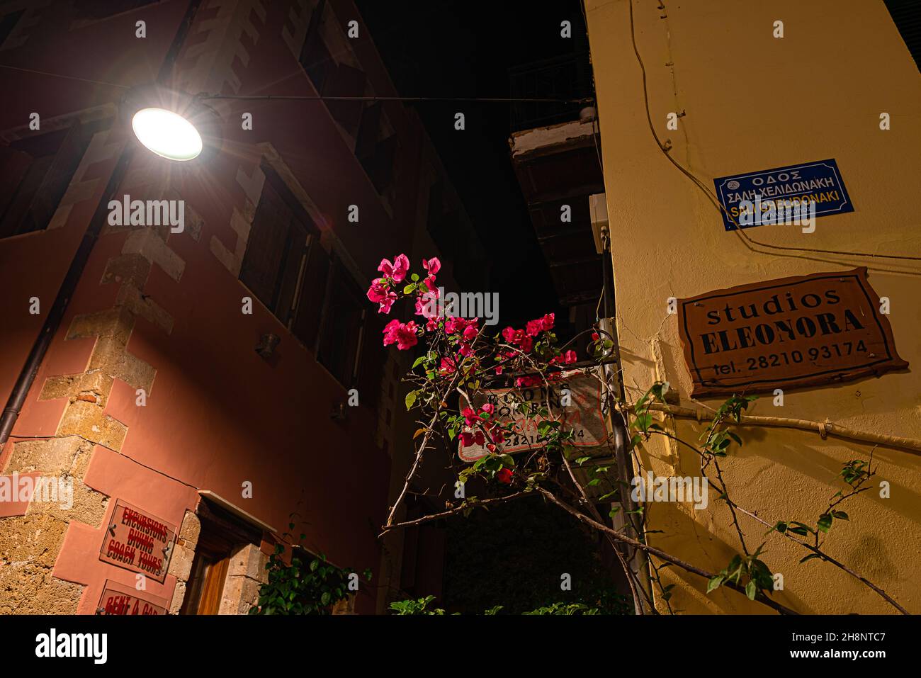 red Bougainvillea illuminated from a streetlight in a narrow alley in the old town of Chania, Crete, Greece, October 15, 2021 Stock Photo