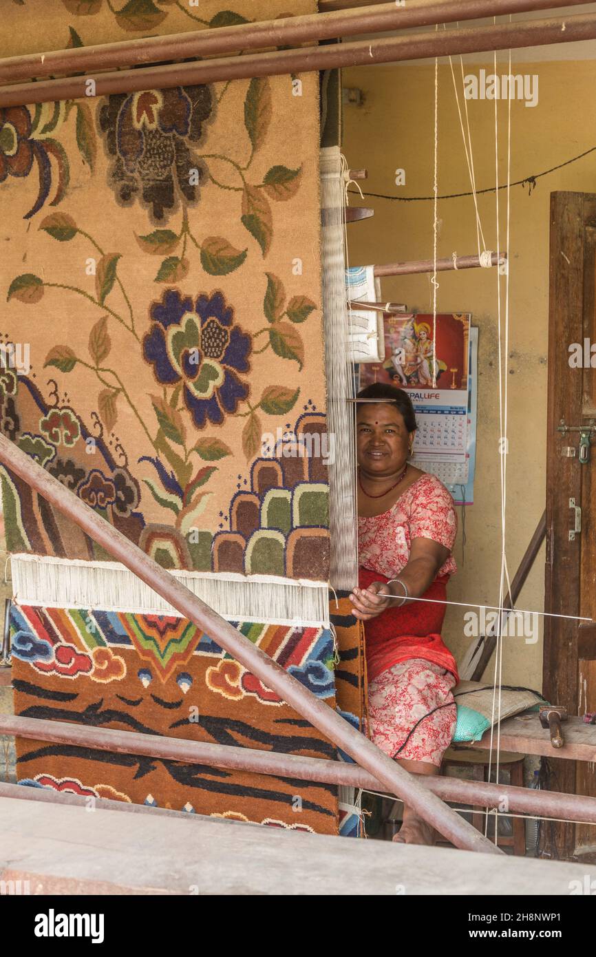 A woman weaving a rug on a wooden foot loom in the medieval village of Bungamati, Nepal. Stock Photo
