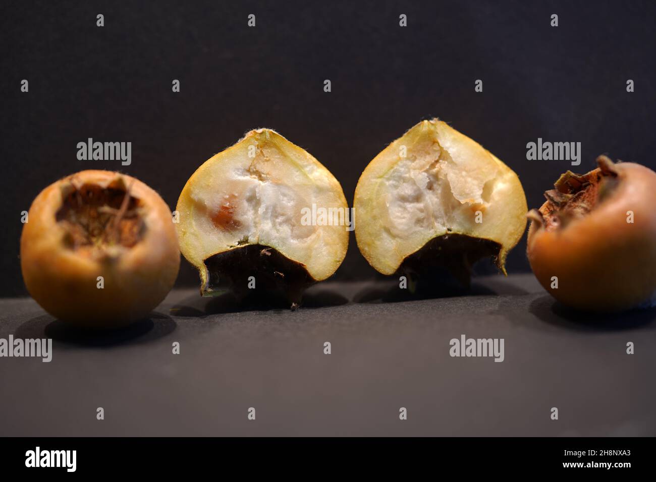 Edible medlar fruits (mespilus germanica, family rosaceae). Medlar fruit is available in winter and in being eaten when bletted. Cross section Mispel Stock Photo