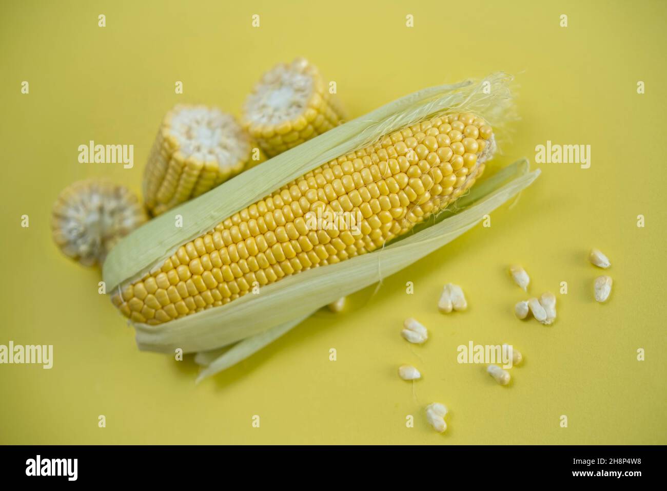 Fresh sweet corn on cobs on yellow background, closeup, top view Stock Photo