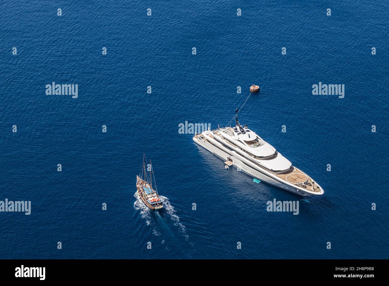 Aerial drone top down photo of luxury exotic yacht with wooden deck anchored in Aegean island with deep blue sea, Greece. Stock Photo