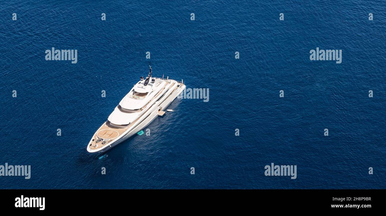 Aerial drone top down photo of luxury exotic yacht with wooden deck anchored in Aegean island with deep blue sea, Greece. Stock Photo