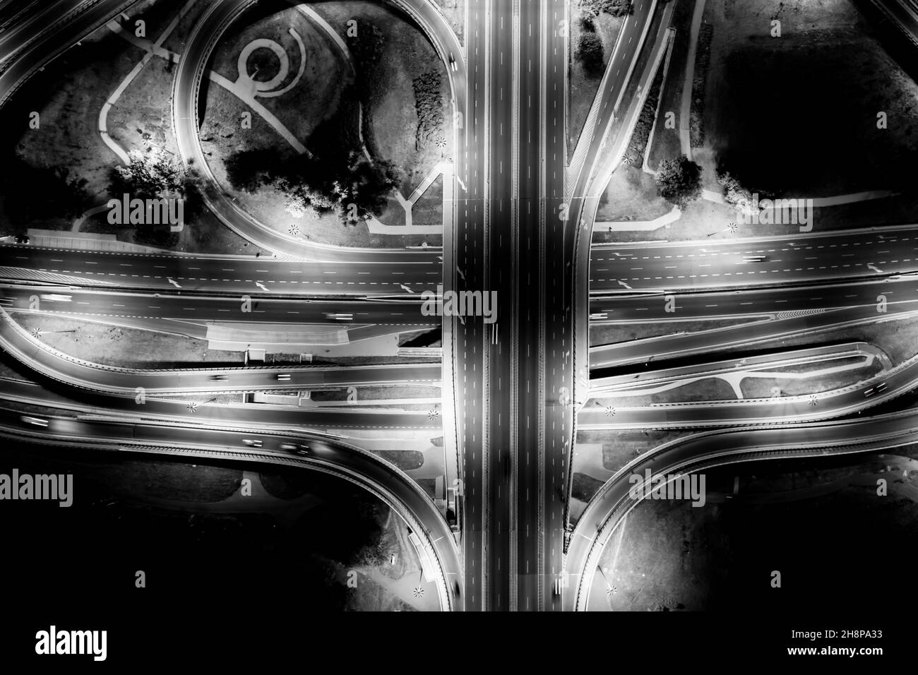 Aerial View Above of Busy Highway Road Junctions at Night. The Intersecting Freeway Road Overpass. Black and White Stock Photo