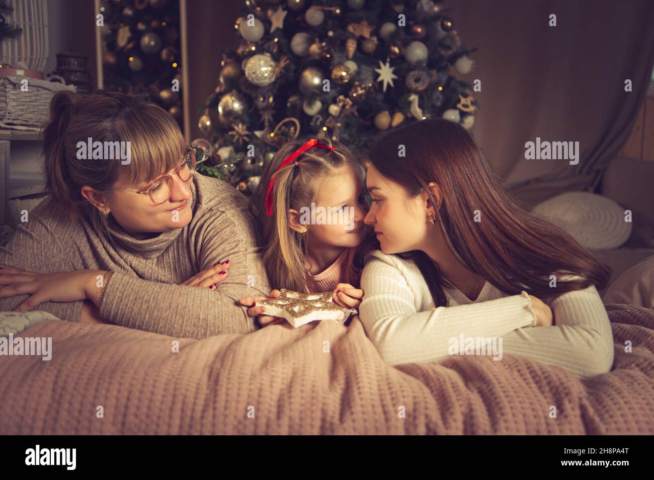 Mom and daughters are lying in bed. Christmas decorations, waiting for the holiday Stock Photo