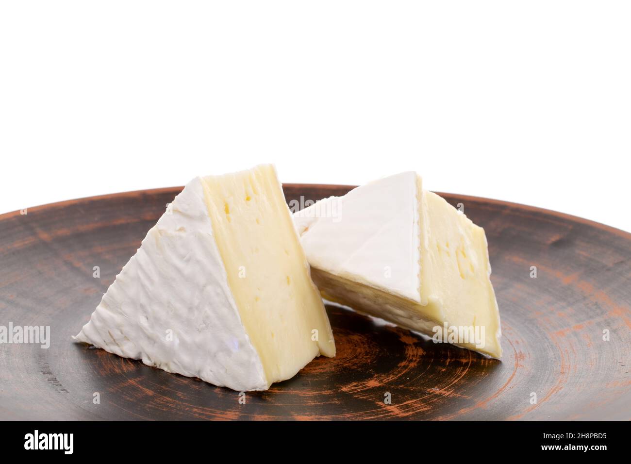 Two fragrant pieces of brie cheese on a ceramic platter, closeup