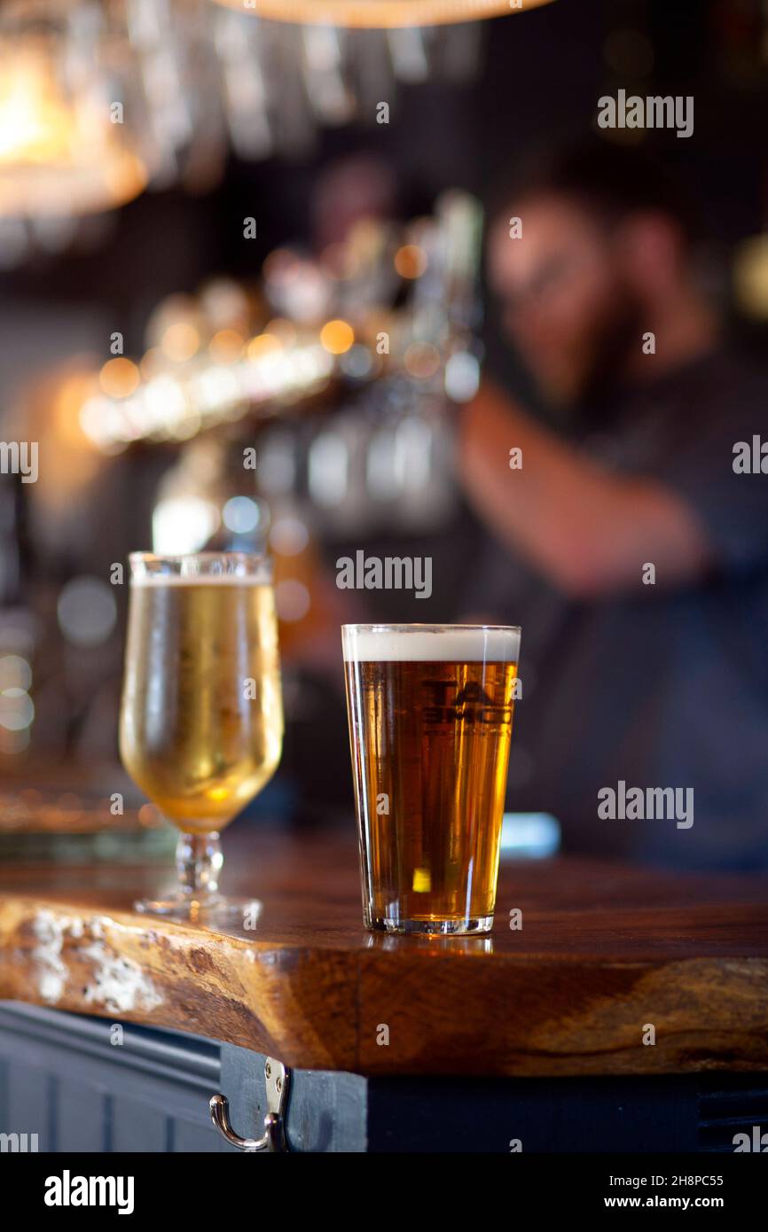 A barman pulls a pint as Pints of bitter and lager sit on the bar at