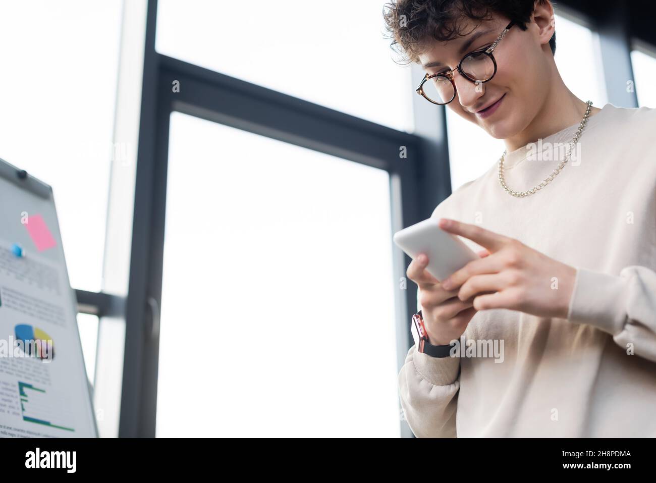 Low angle view of young businessman using mobile phone near flip chart in office,stock image Stock Photo