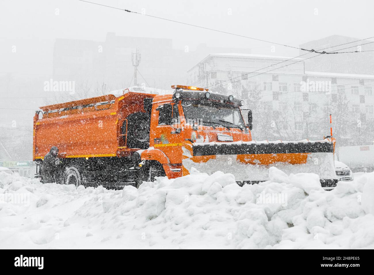 A large orange snowplow stands on the road before snow removal. Special equipment for snow removal cyclone. Stock Photo