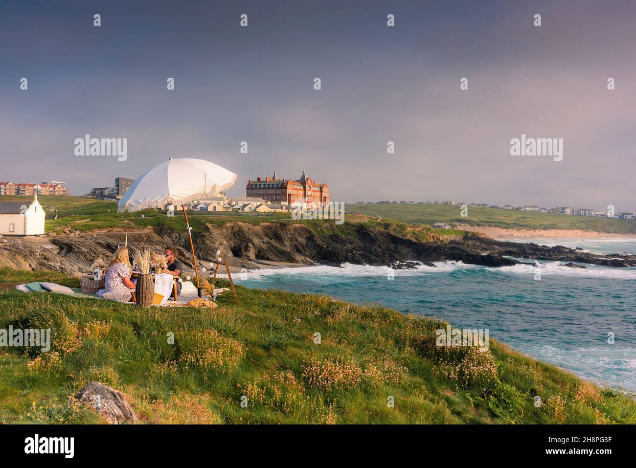 A couple celebrating a special occasion with a romantic evening picnic on Towan Head in Newquay in Cornwall. Stock Photo