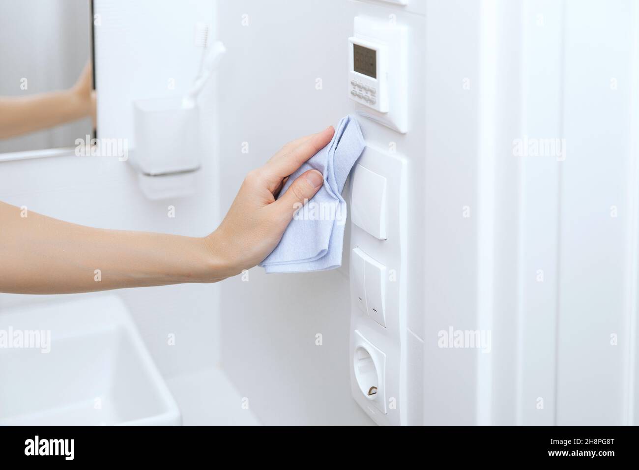 Cleaning switches and sockets with a microfiber cloth. Sanitize surfaces prevention in hospital and public spaces against corona virus. Woman hand Stock Photo
