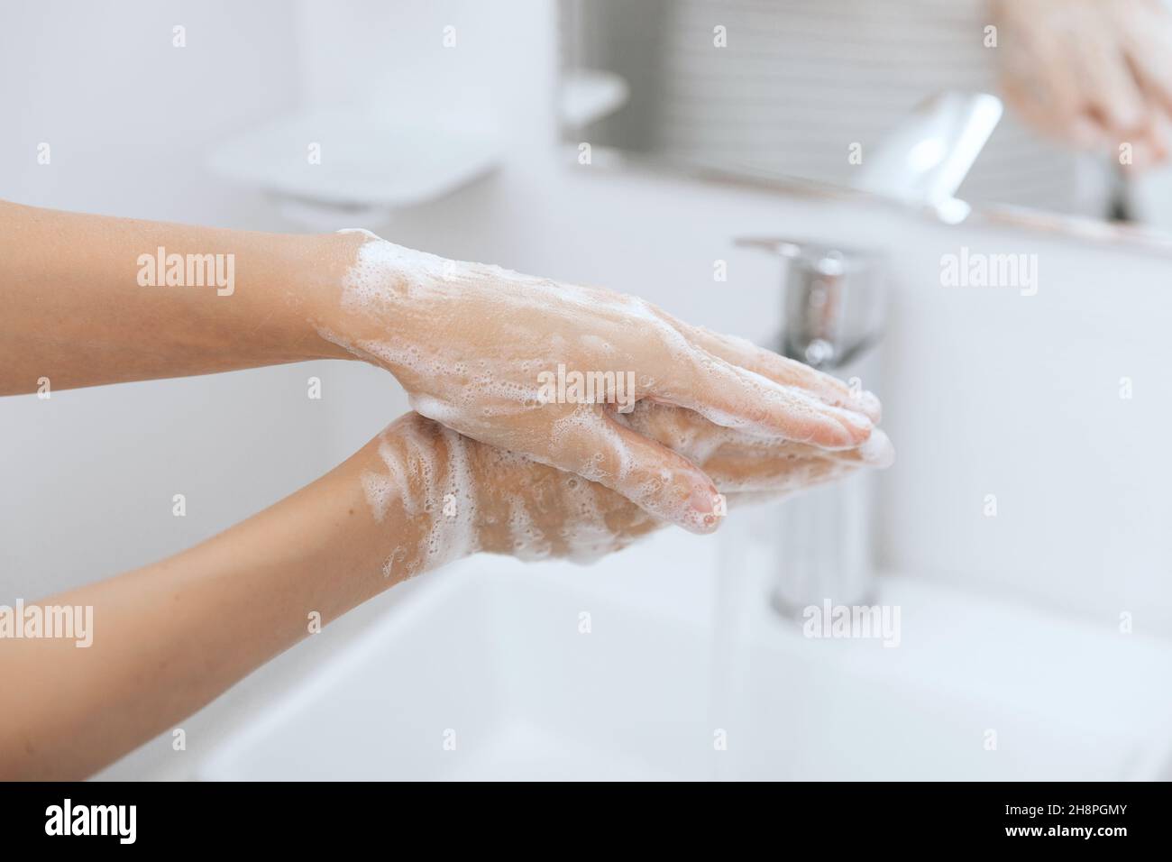 Washing hands under the flowing water tap. Hygiene concept hand detail. Washing hands rubbing with soap for corona virus prevention, hygiene to stop Stock Photo