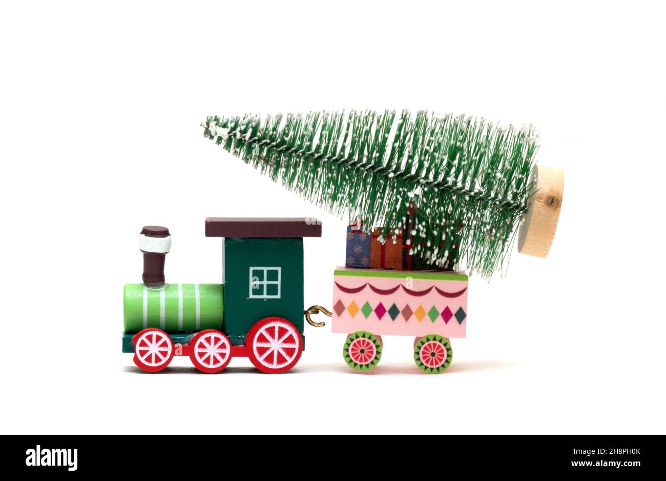 A toy locomotive is carrying a Christmas tree. Feast of the Nativity of Christ. Isolated photo for design. Stock Photo