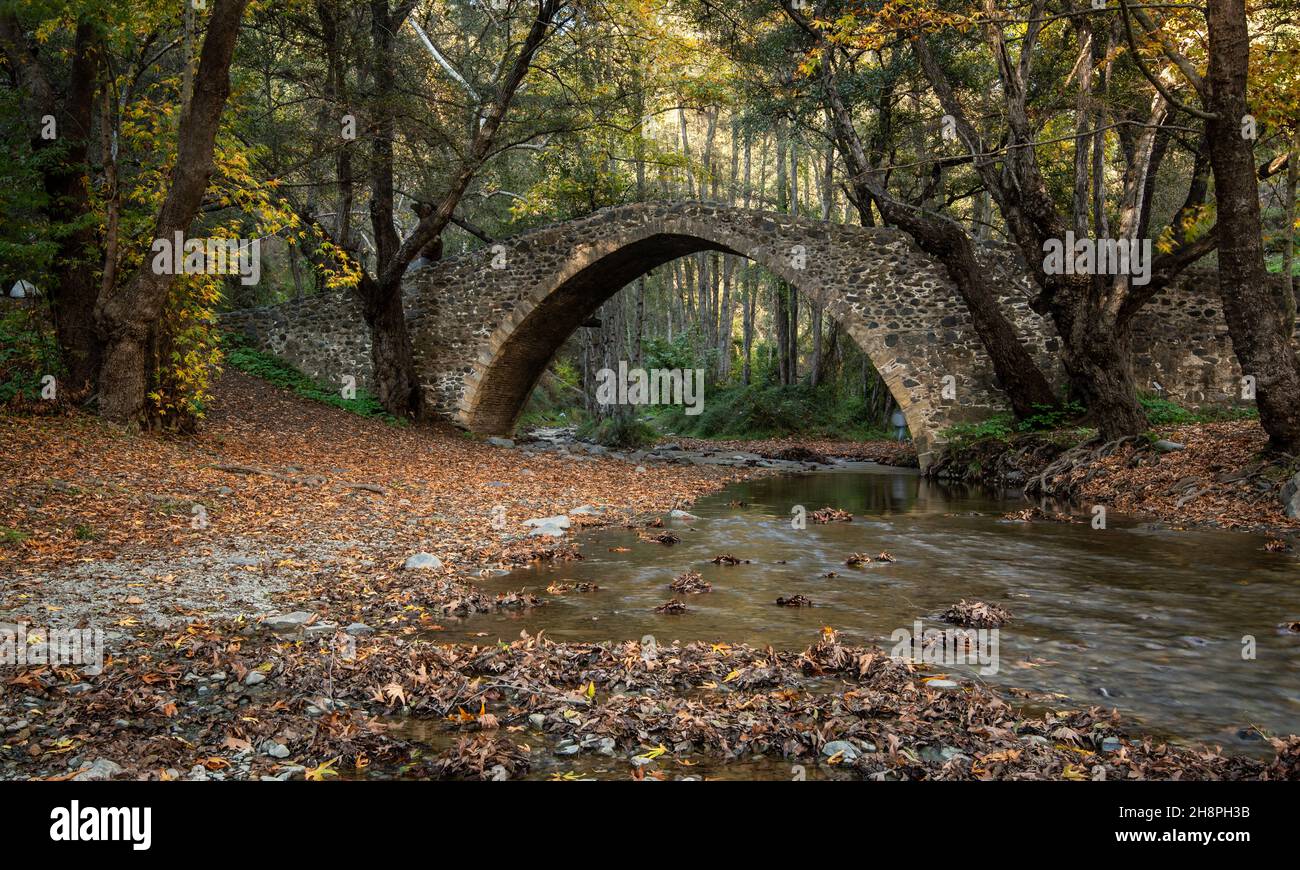Autumn landscape with river flowing below ancient stoned bridge and ...