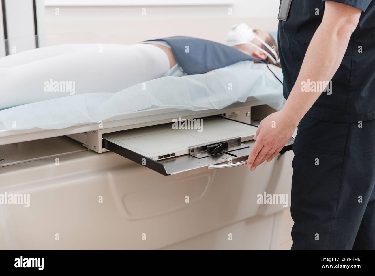 Doctor taking xray of patient lying on gurney. Hospital radiology room