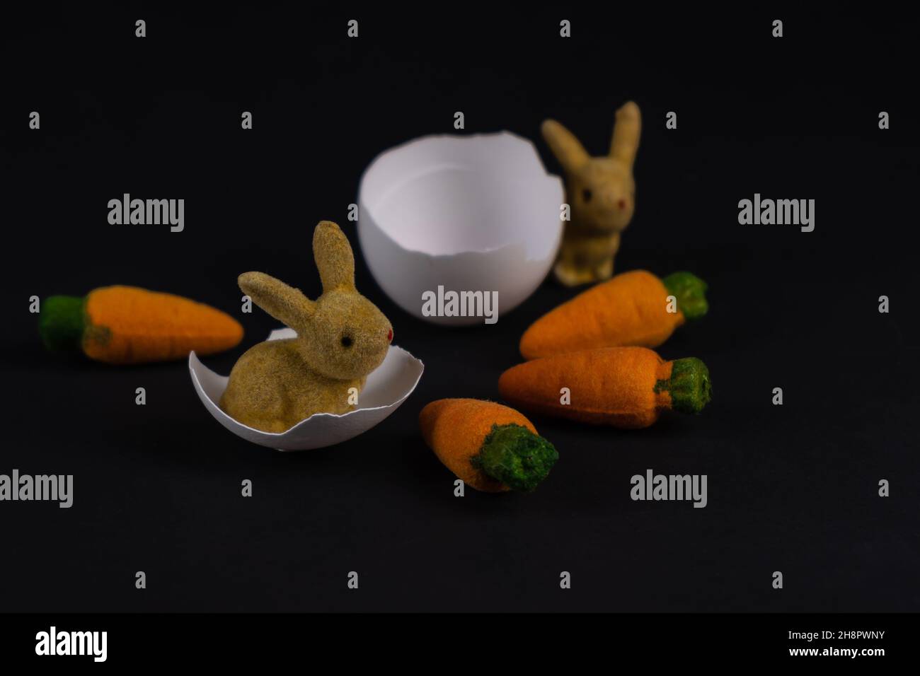 two decorative Easter bunnies with eggshells and four carrots Stock Photo