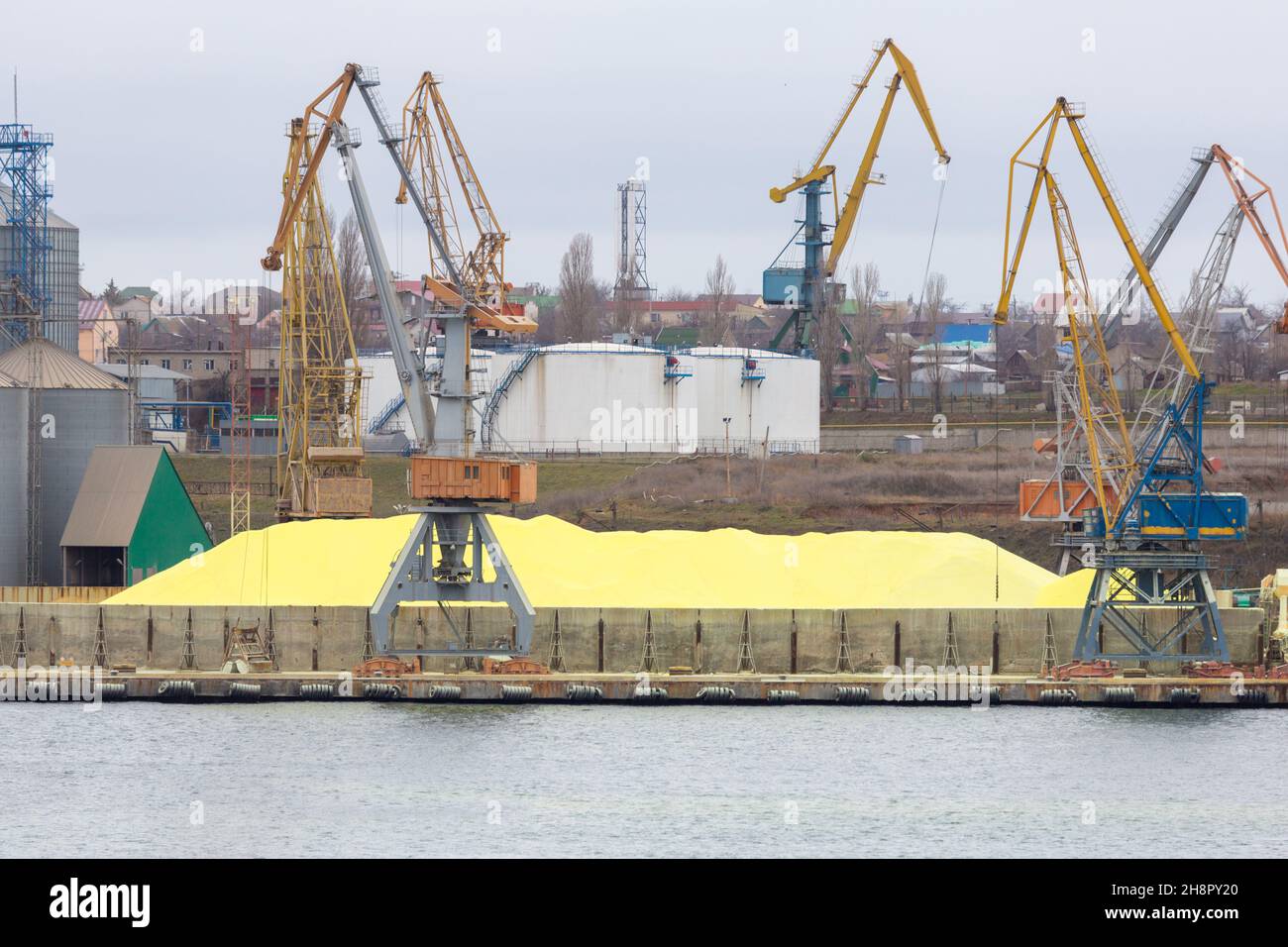 Huge stockpile of industrial sulfur that will be shipped around world. Industrial Sulfur Stockyard and Pile. Huge stockpile of sulfur in sea port at b Stock Photo