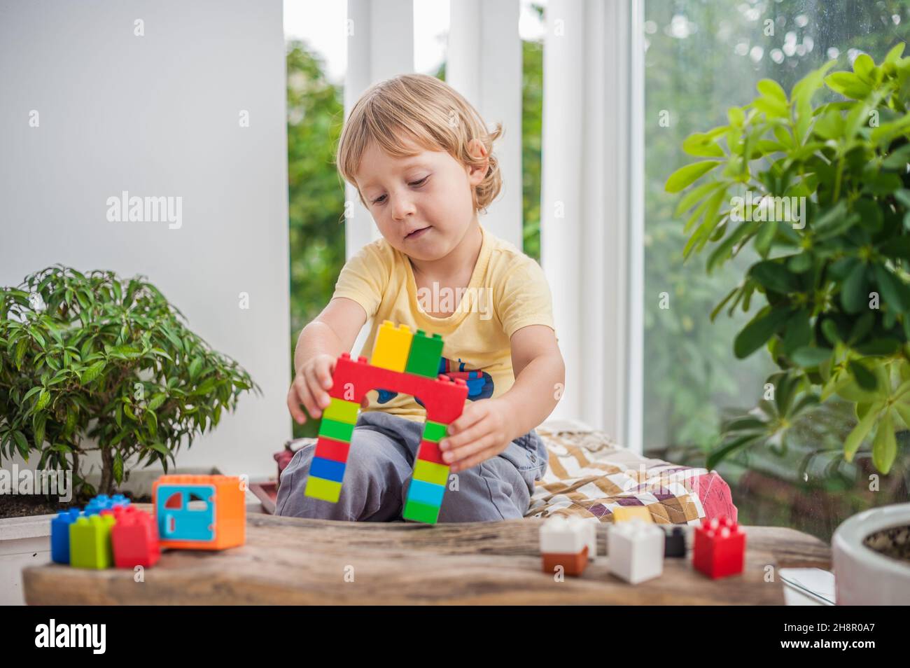 Cute little kid boy with playing with lots of colorful plastic blocks ...