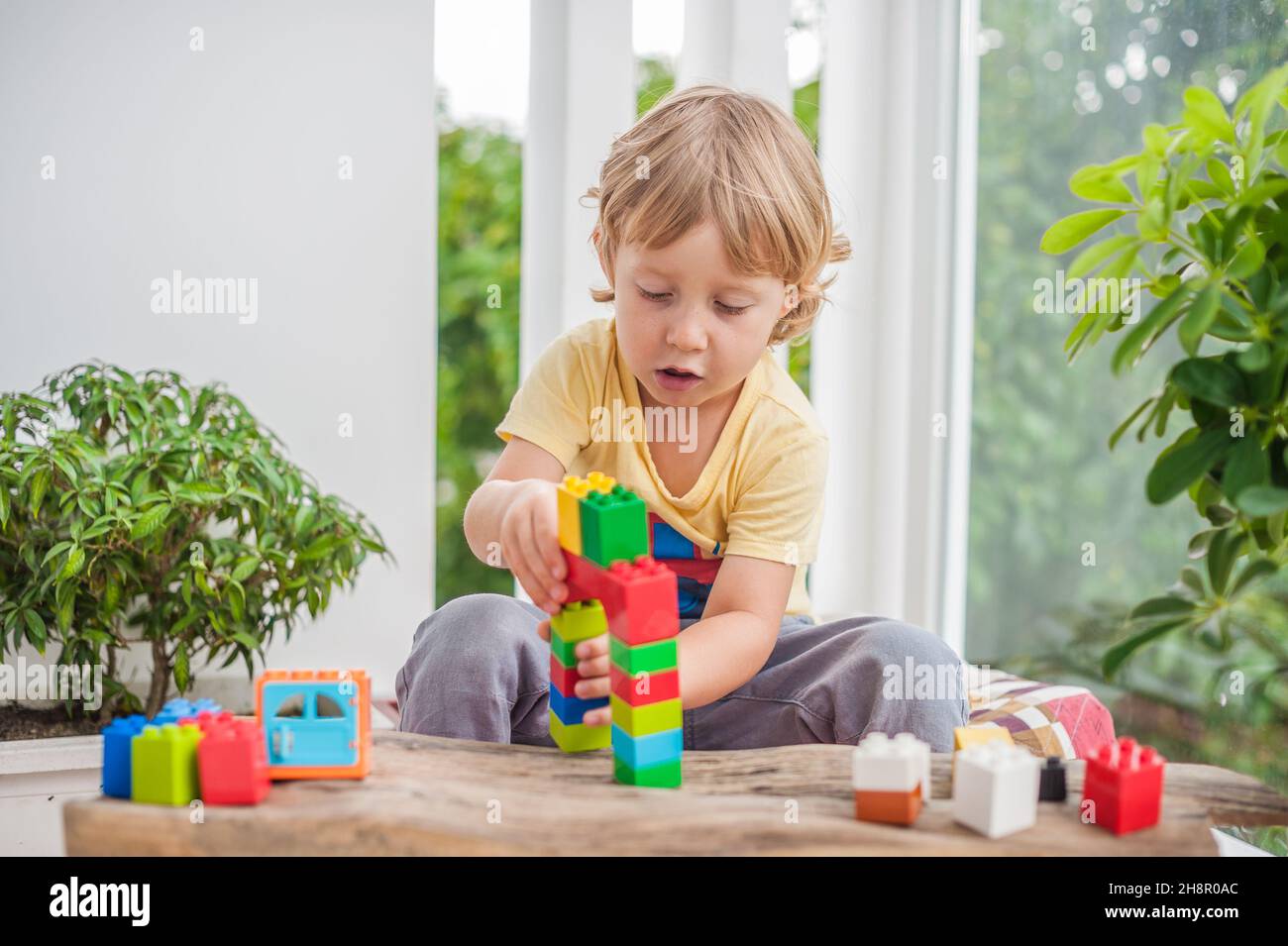 Cute little kid boy with playing with lots of colorful plastic blocks ...