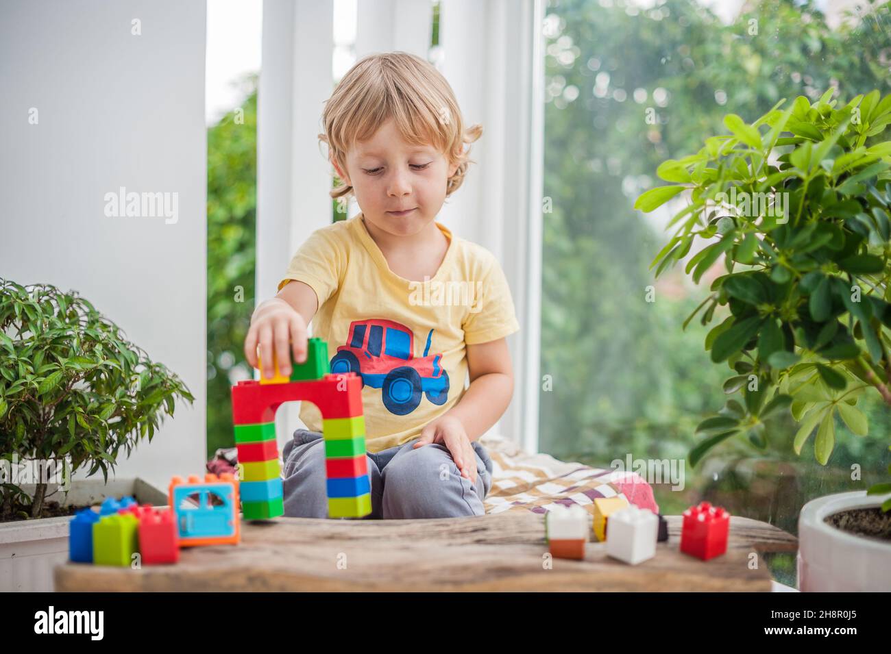 Cute little kid boy with playing with lots of colorful plastic blocks ...