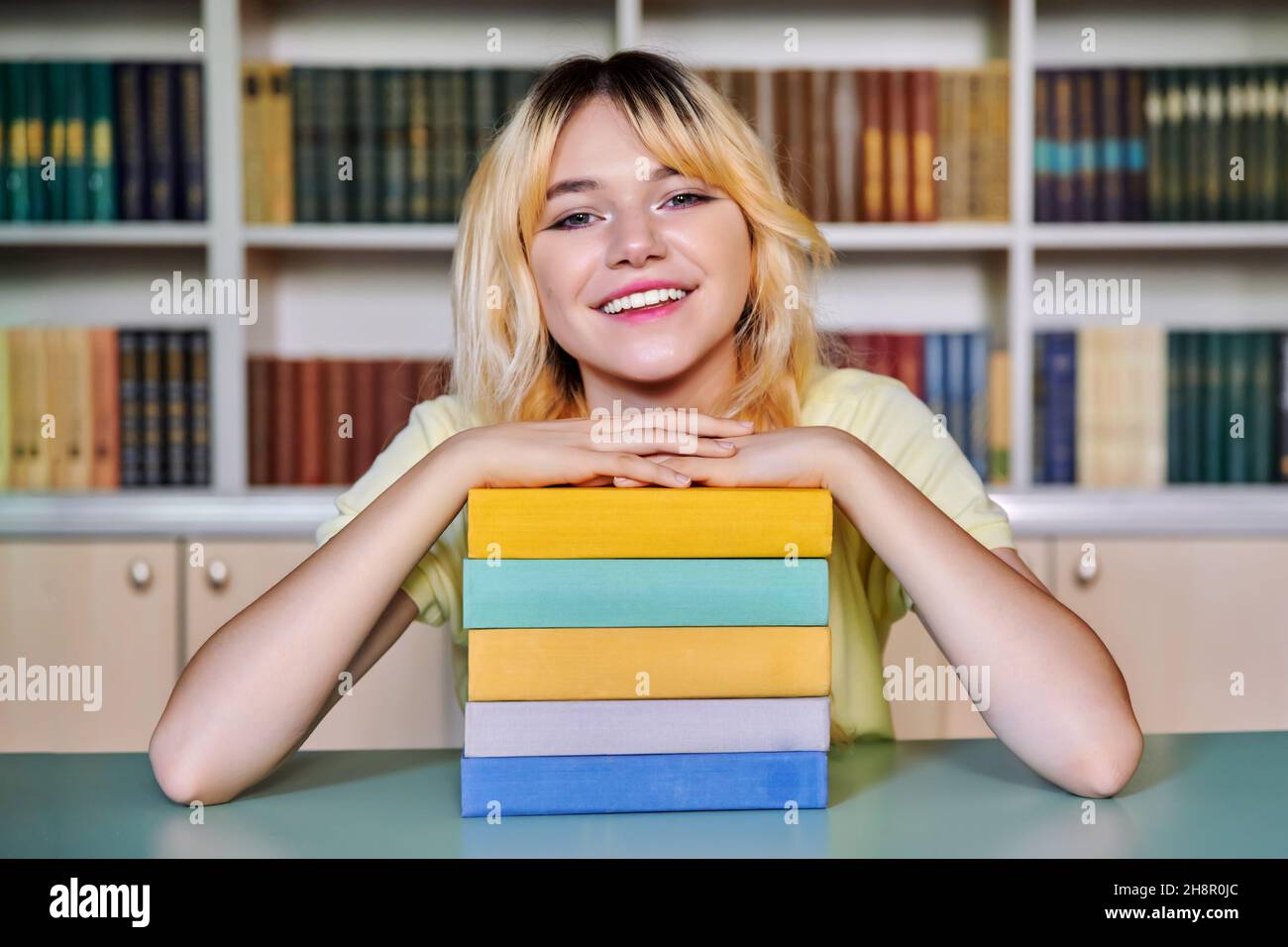 Female teenage high school student looking at camera with books in library Stock Photo