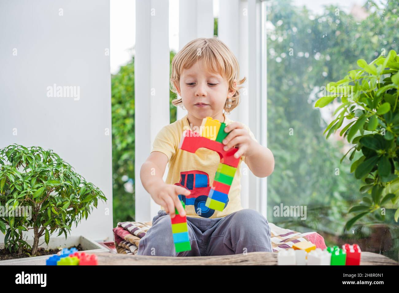 Cute little kid boy with playing with lots of colorful plastic blocks ...
