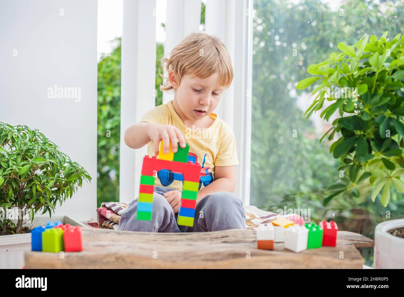 Cute little kid boy with playing with lots of colorful plastic blocks ...