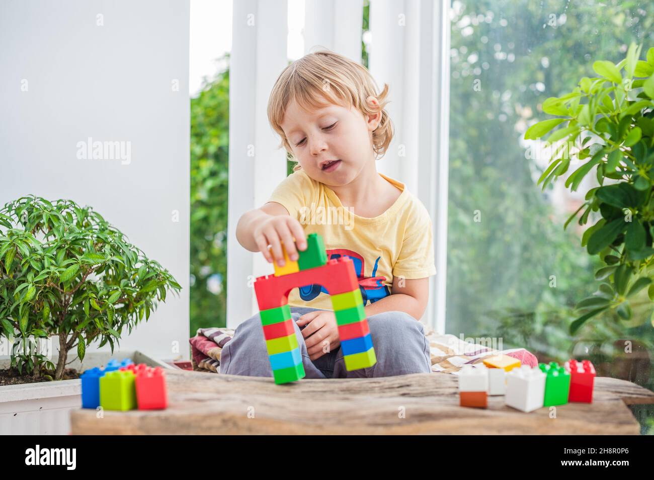 Cute little kid boy with playing with lots of colorful plastic blocks ...