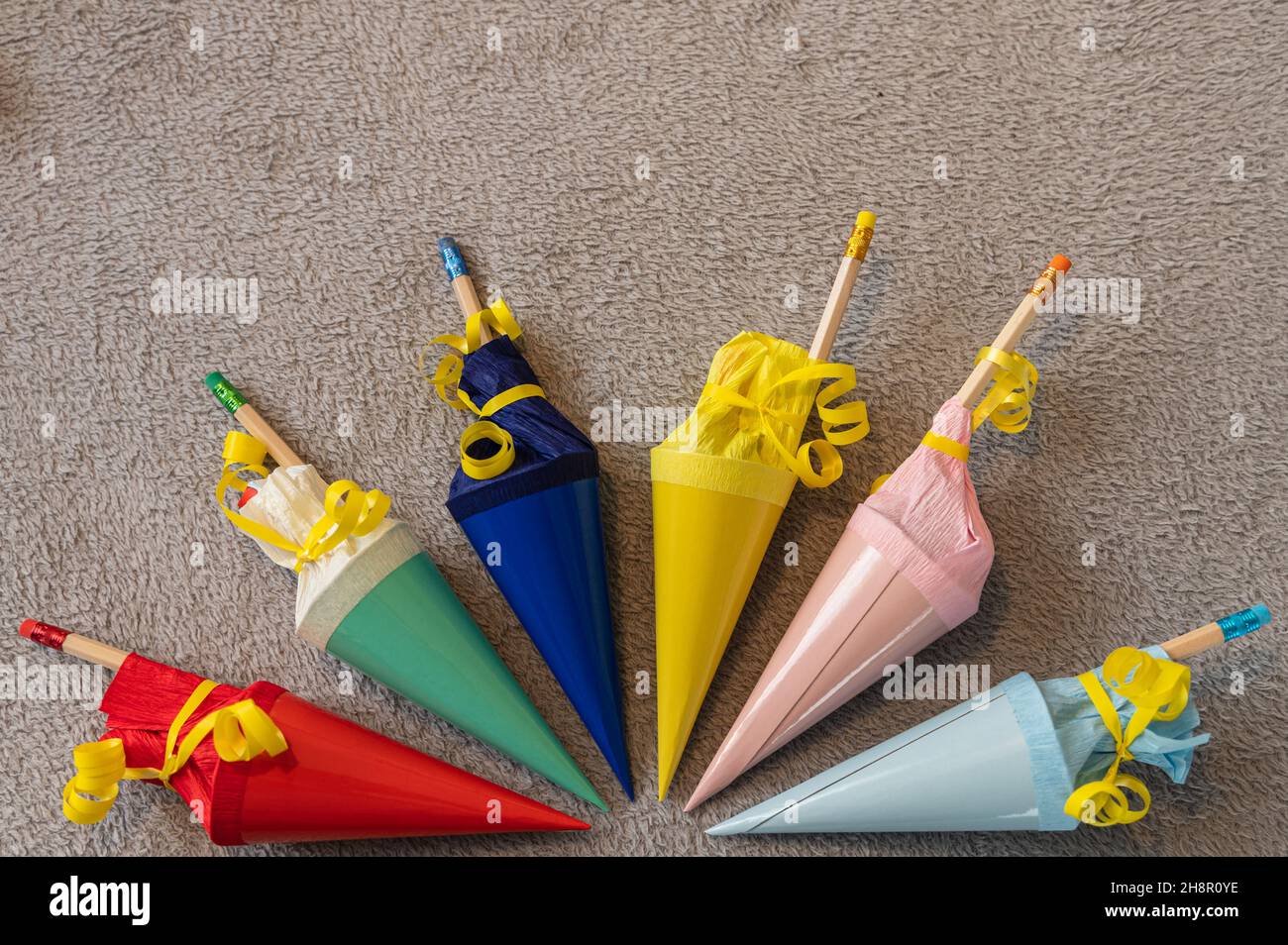 six colorful small filled sugar cones for back to school arranged in a semicircle on a gray background Stock Photo