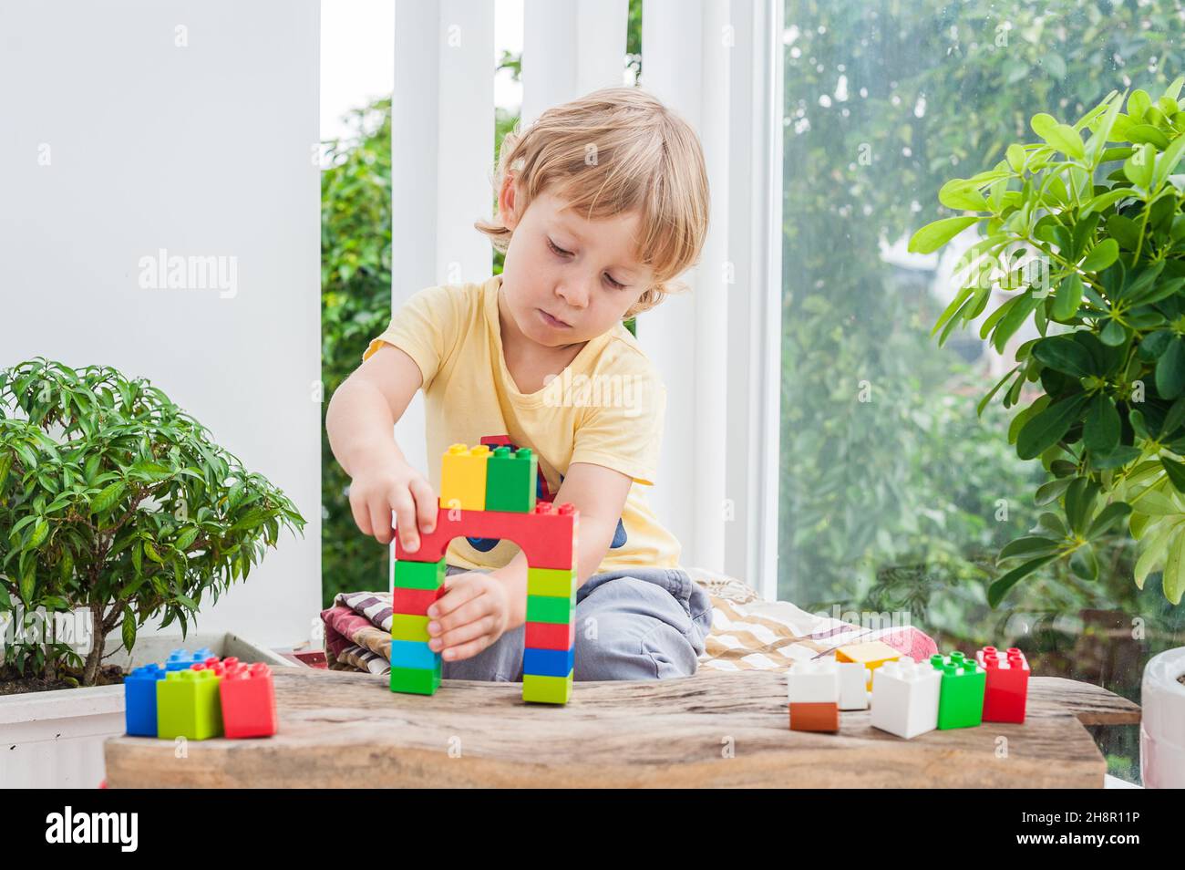Cute little kid boy with playing with lots of colorful plastic blocks ...