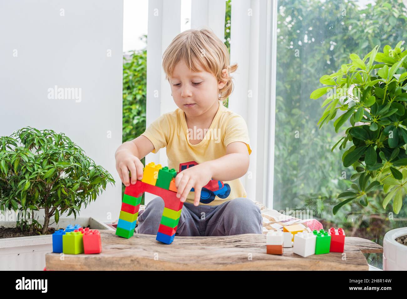 Cute little kid boy with playing with lots of colorful plastic blocks ...