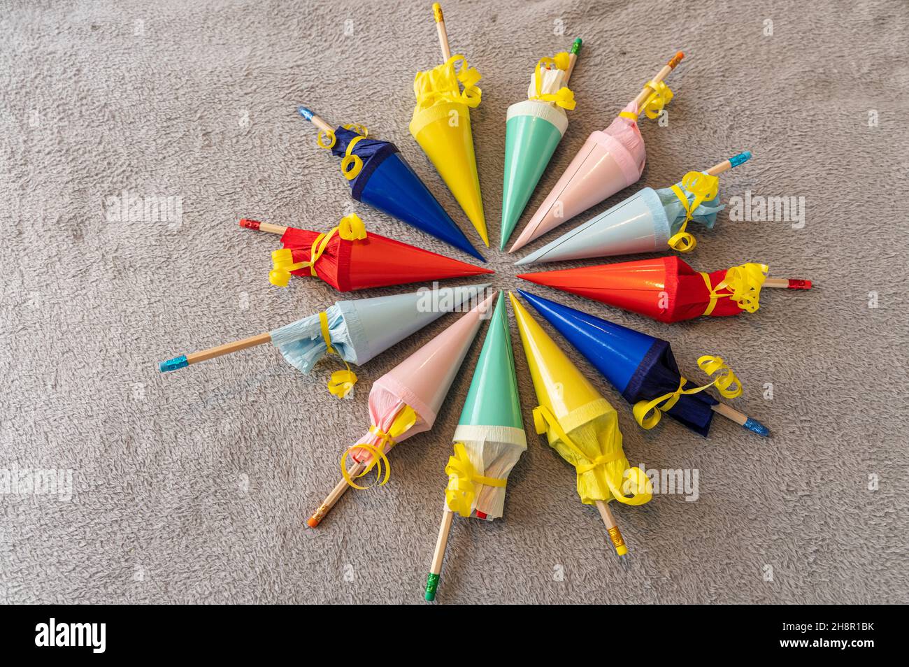 twelve colorful small filled sugar cones for back to school arranged in a circle on a gray background Stock Photo