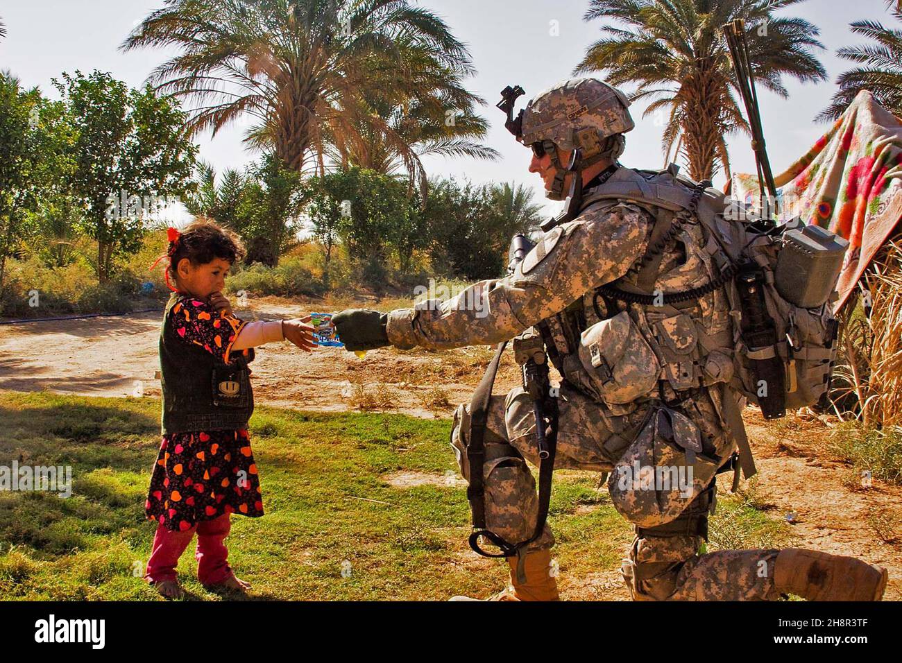 U.S. Army 1st Lt. Austin Huckabee, from San Angelo, Texas, hands a small bag of candy to a young Iraqi girl during a patrol in a small village north of Taji, Iraq, Nov. 12. American Soldiers and the 34th Iraqi Army Brigade performed a joint air assault mission and patrol to check on living conditions of the small village. Stock Photo