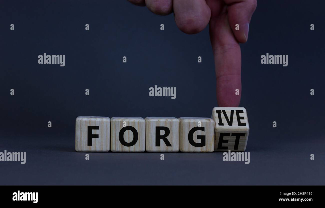 Forgive and forget symbol. Businessman turns a wooden cube and changes the word forgive to forget. Beautiful grey background, copy space. Business, ps Stock Photo