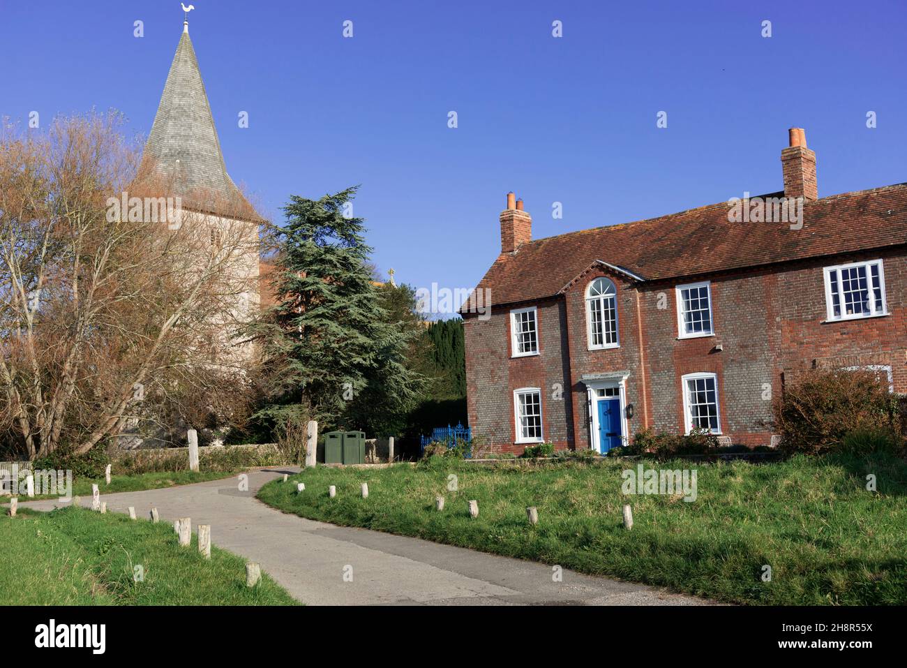 The village green at Bosham,which overlooks the sea,showing grade II listed Brook House built in 1743 and the Holy Trinity Church,Brook Lane,Bosham,UK Stock Photo