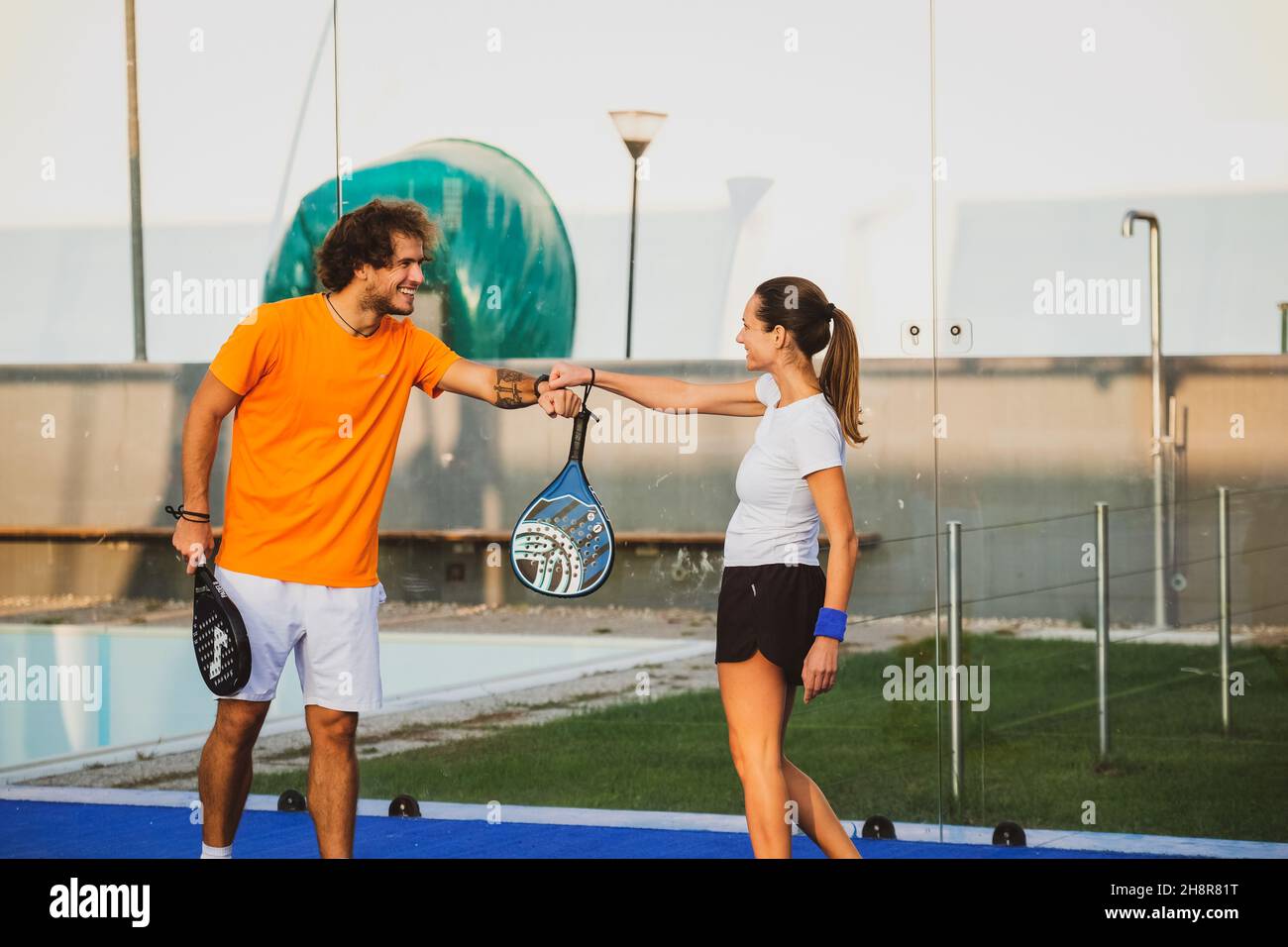 Two padel player greet each other doing fist bump - Padel friends say hello at the time of the covid Stock Photo