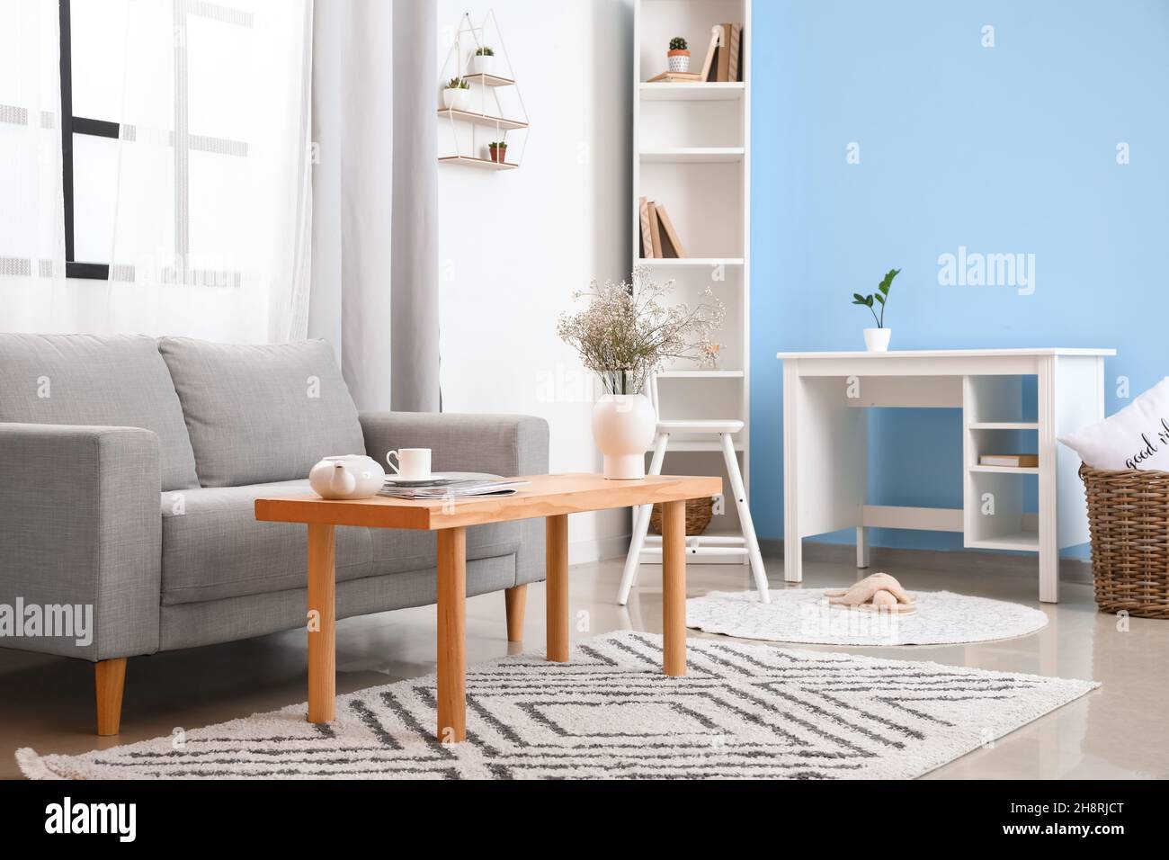 Interior of light living room with grey sofa and wooden table Stock ...
