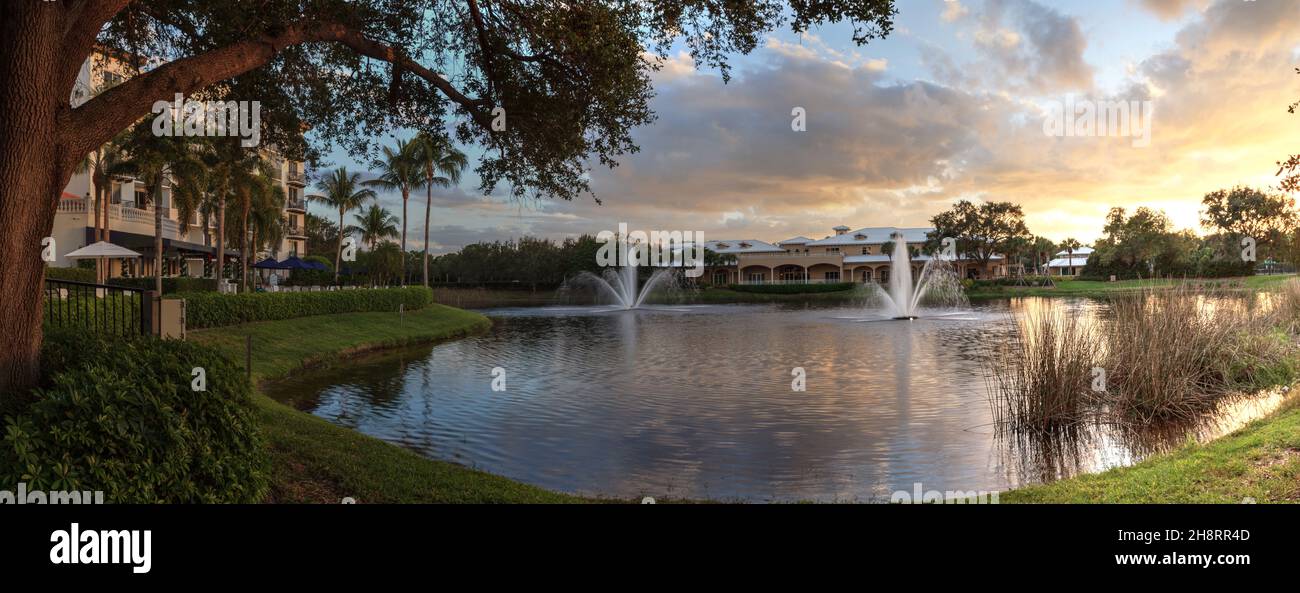 Two large fountains spout up from a tranquil pond in the tropics at sunset. Stock Photo