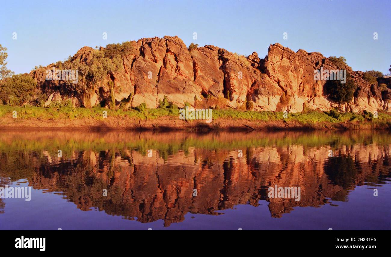 Cliffs of Geikie Gorge glowing red soon before sunset with reflections in the Fitzroy River near Fitzroy Crossing, Western Australia Stock Photo