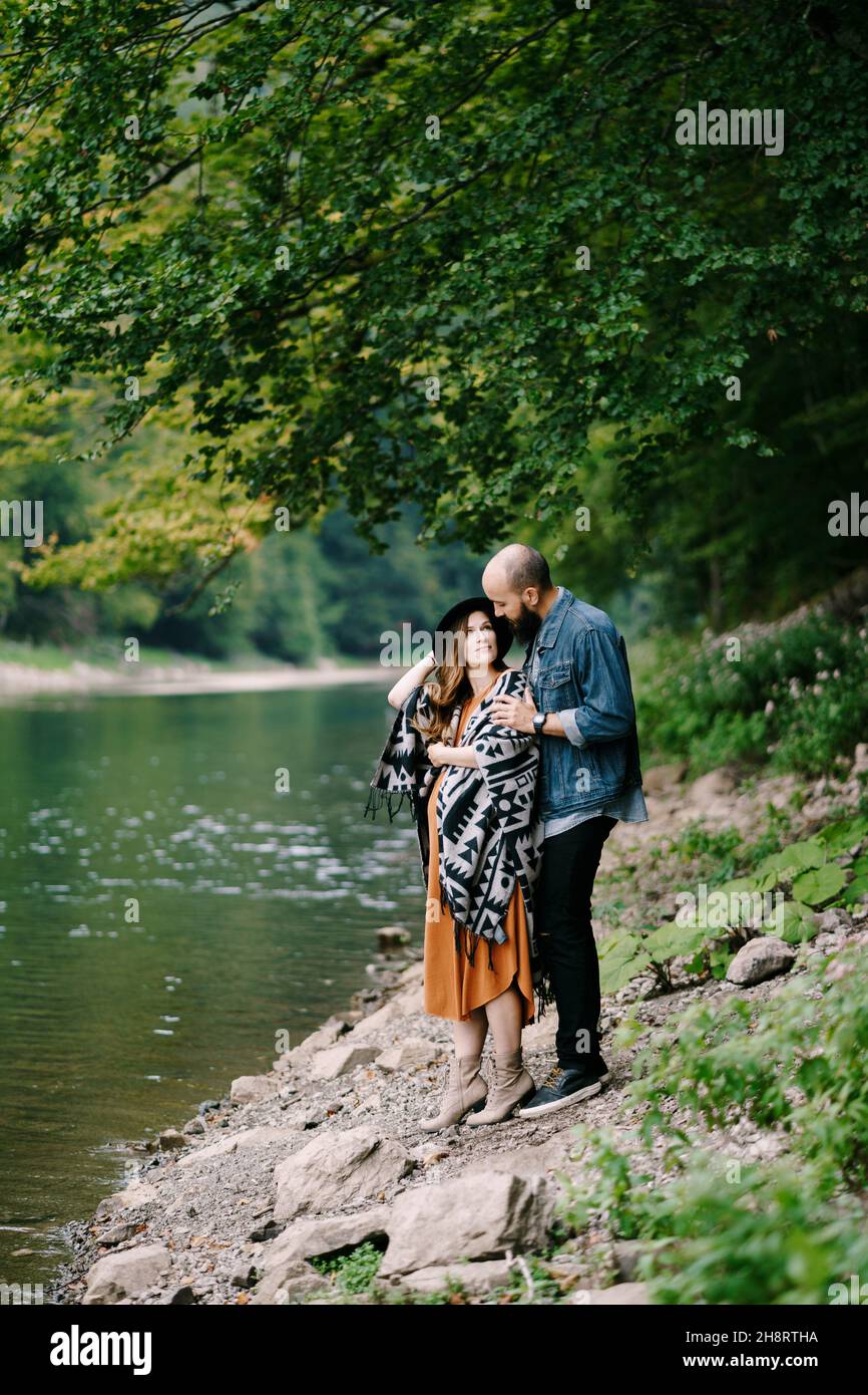 Man hugs the shoulders of a pregnant woman by the lake Stock Photo - Alamy