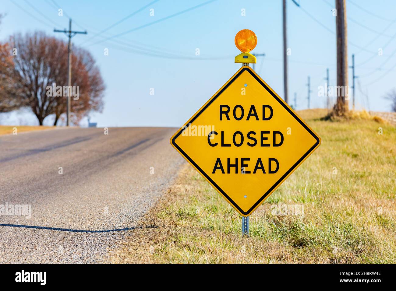 Yellow road closed ahead sign on rural road. Road construction, repair and travel safety concept. Stock Photo