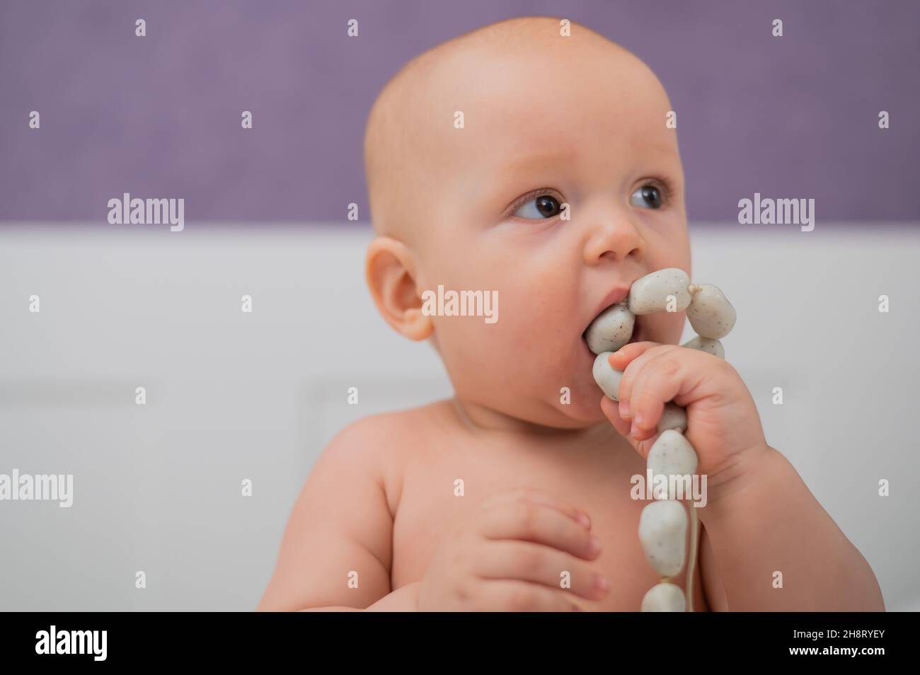 Baby boy gnaws wooden teething boxes. Eco friendly toy. Stock Photo