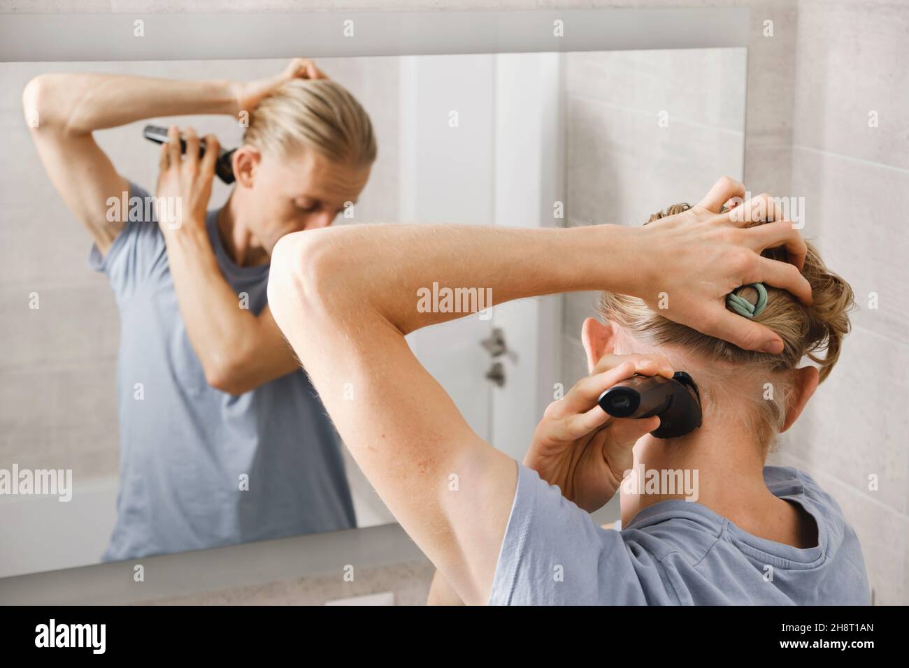 Man shaving whiskers hair by himself, self haircut at home in front of