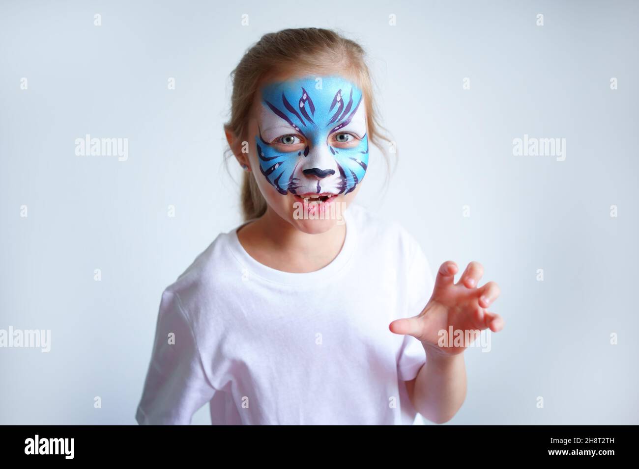 A girl with aqua makeup in the form of a blue water tiger zodiac depicts a tiger on a white background, a concept symbol of the new 2022 year. Stock Photo