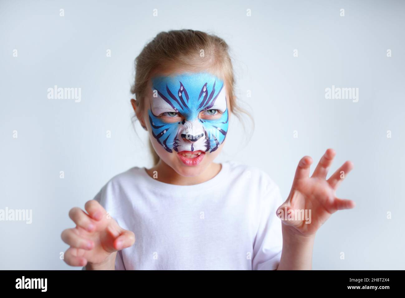 A girl with aqua makeup in the form of a blue water tiger zodiac depicts a tiger on a white background, a concept symbol of the new 2022 year. Stock Photo