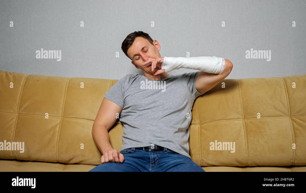 Brunet man picks nose with broken arm Stock Photo