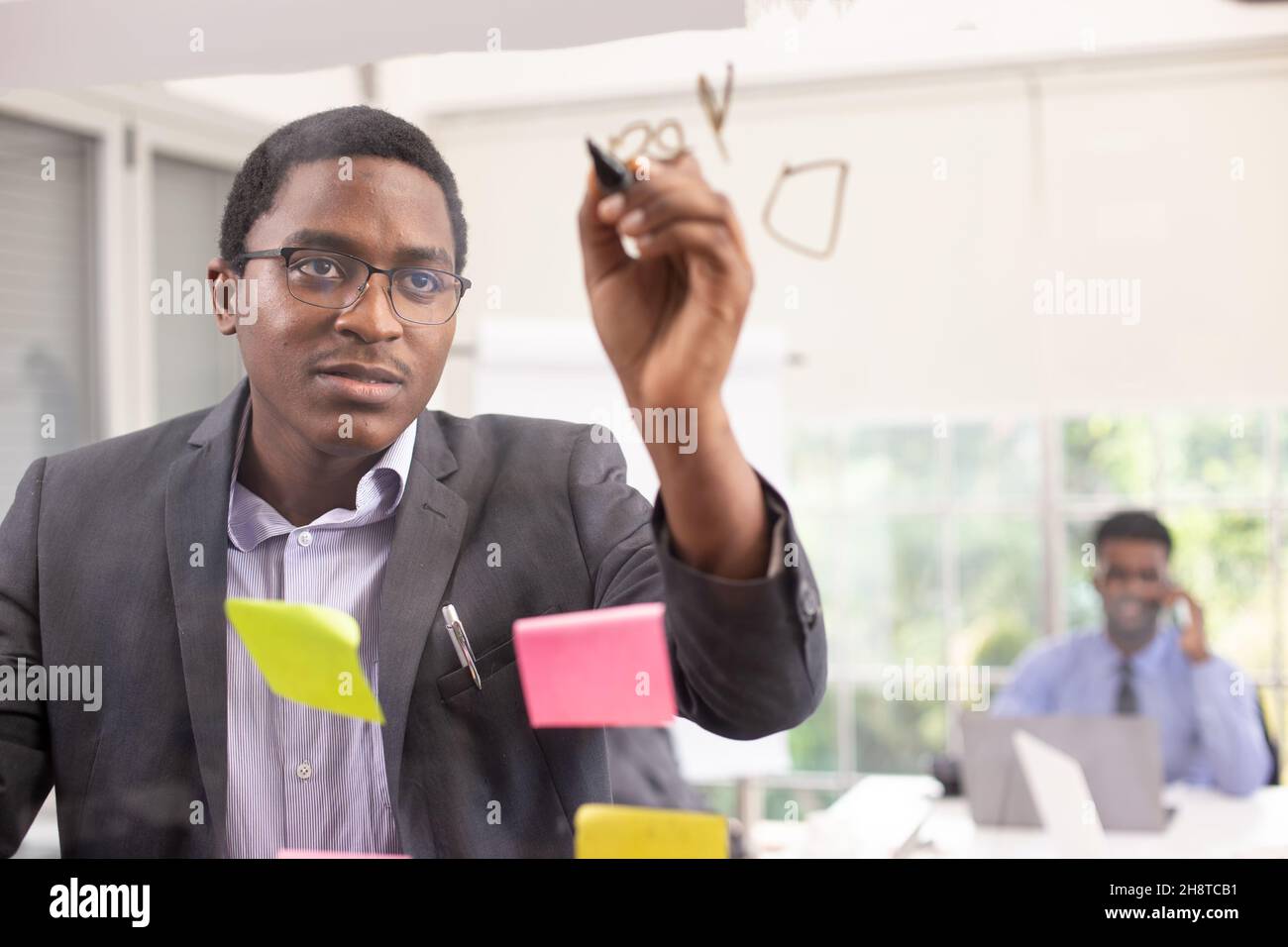 African American young man writing note on a transparent wipe board and
