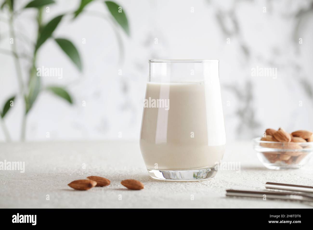 Vegan almond milk in glass with nuts on white background. Copy space. Healthy vegetarian food. selective focus. Non dairy alternative milk Stock Photo